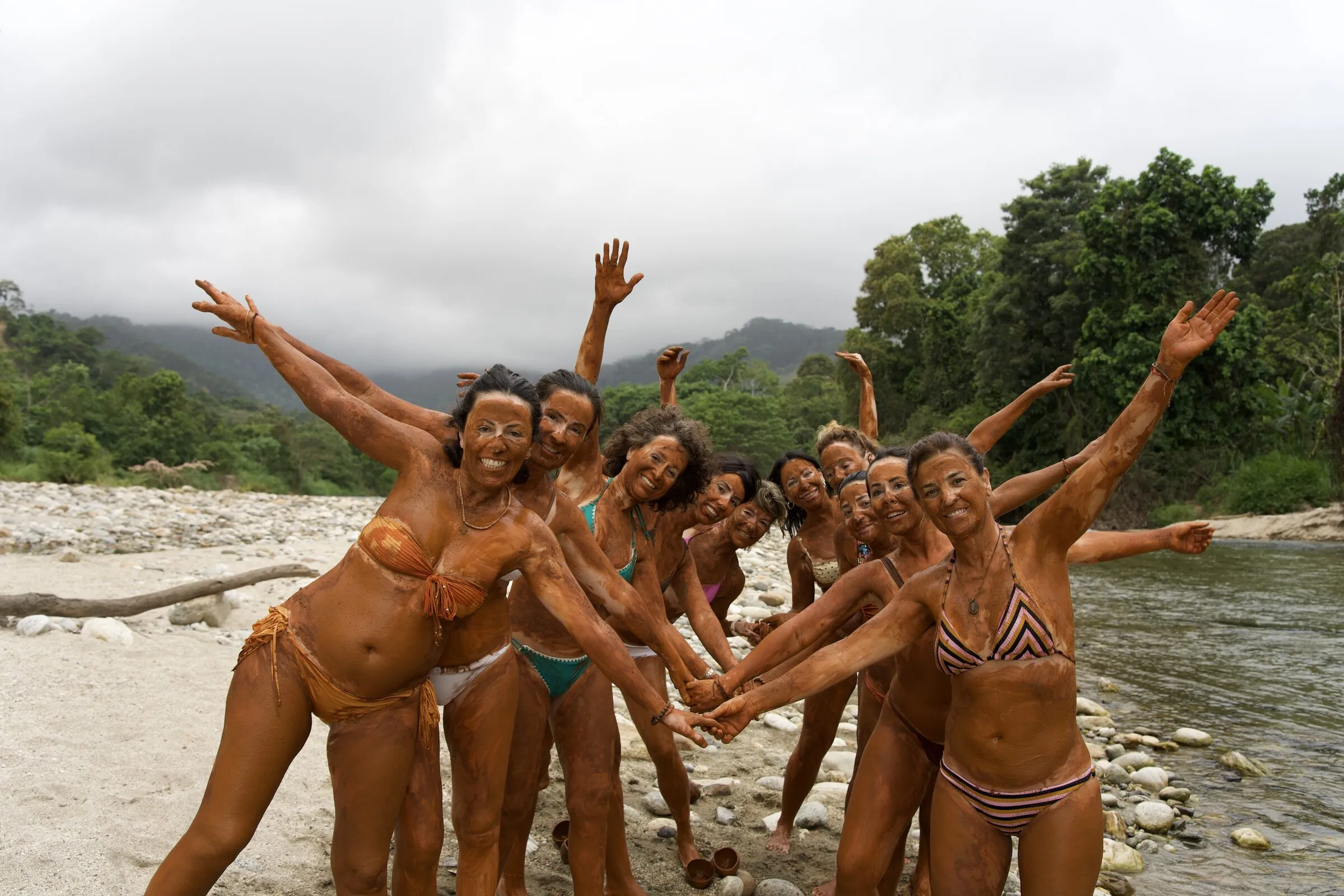 Grupo cubierto de arcilla celebrando en el río